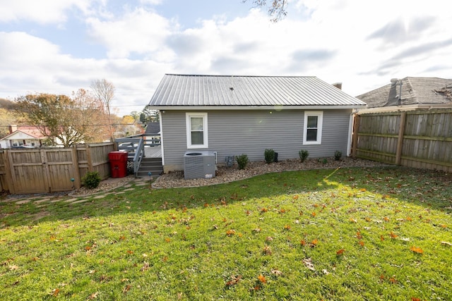 rear view of property with central AC unit, a deck, and a yard