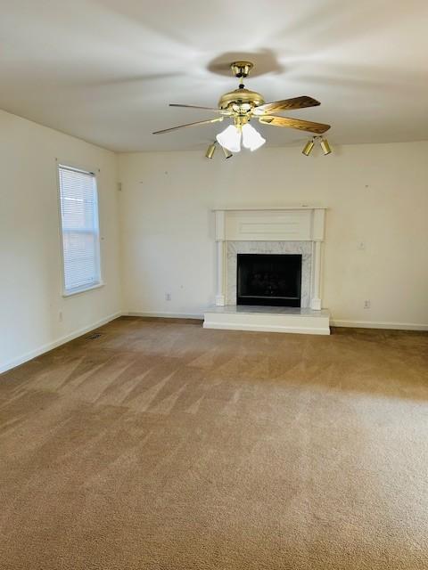 unfurnished living room featuring carpet, ceiling fan, and a high end fireplace