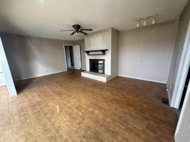 unfurnished living room with dark hardwood / wood-style flooring, a brick fireplace, a textured ceiling, and ceiling fan