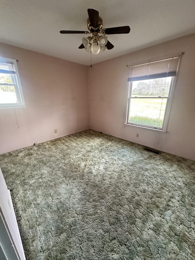 carpeted empty room featuring ceiling fan and a textured ceiling