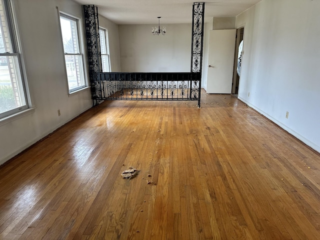 spare room featuring wood-type flooring and a chandelier