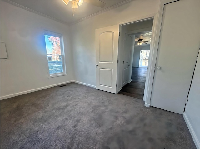 unfurnished bedroom with dark colored carpet, ceiling fan, and ornamental molding