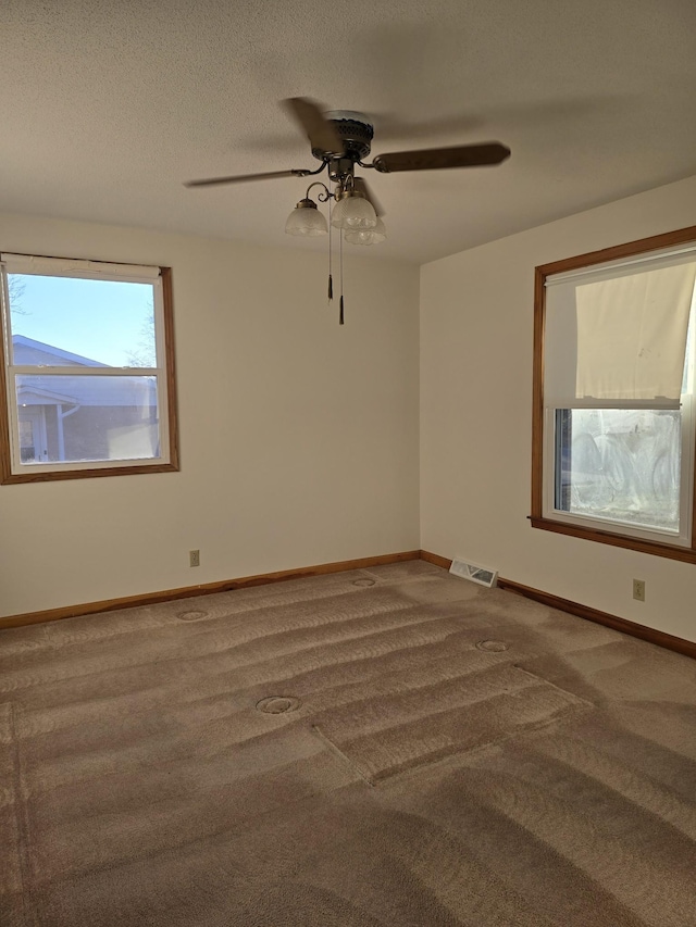 carpeted empty room with ceiling fan and a textured ceiling