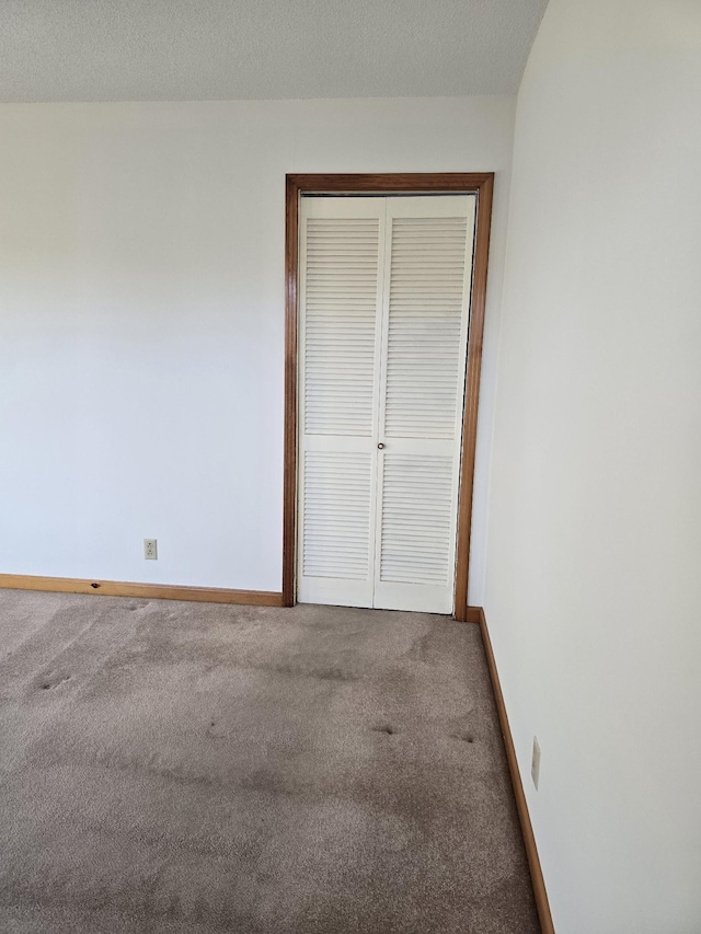 unfurnished bedroom with carpet, a textured ceiling, and a closet