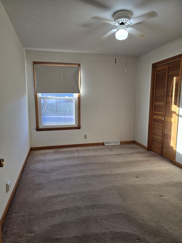 carpeted spare room featuring ceiling fan and a textured ceiling