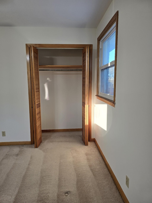 unfurnished bedroom featuring light colored carpet and a closet