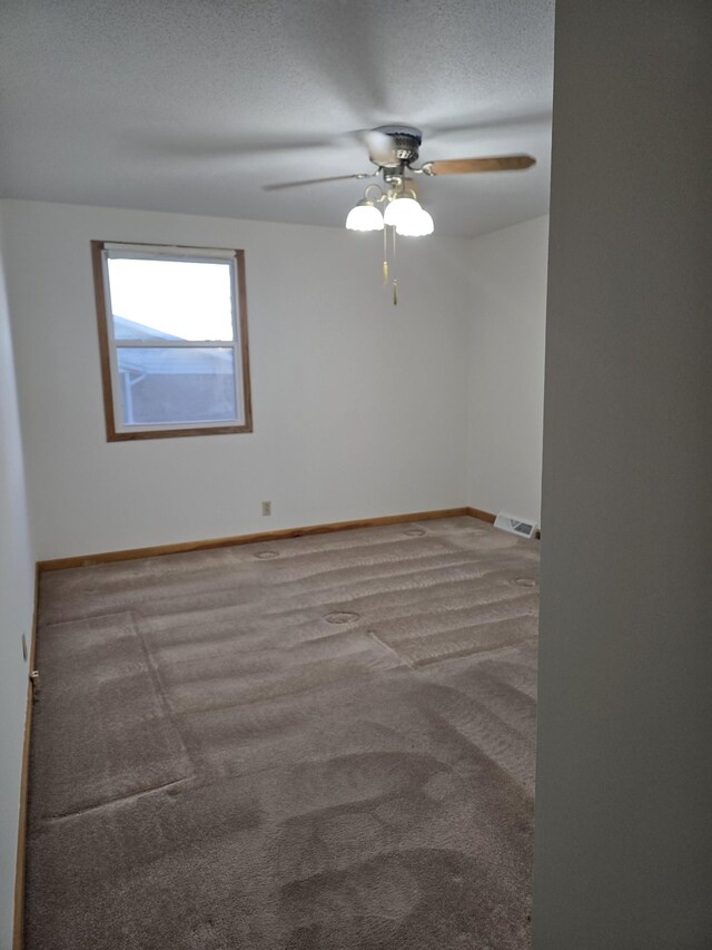 carpeted empty room featuring ceiling fan and a textured ceiling