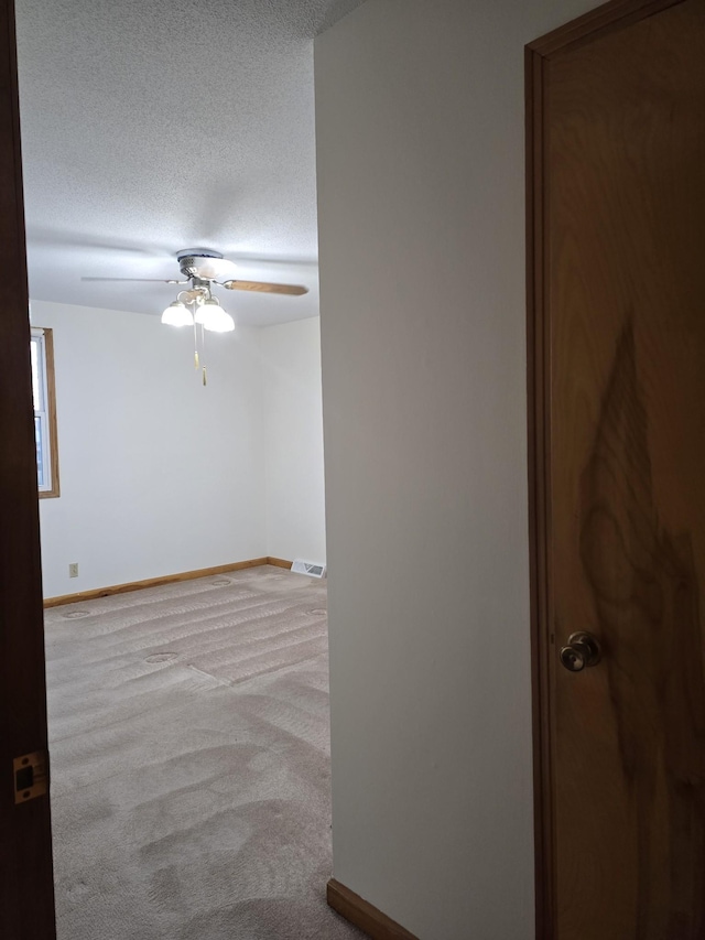 spare room featuring a textured ceiling, light colored carpet, and ceiling fan