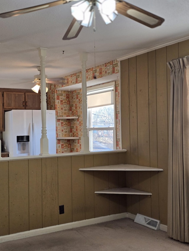 kitchen featuring wooden walls and white fridge with ice dispenser