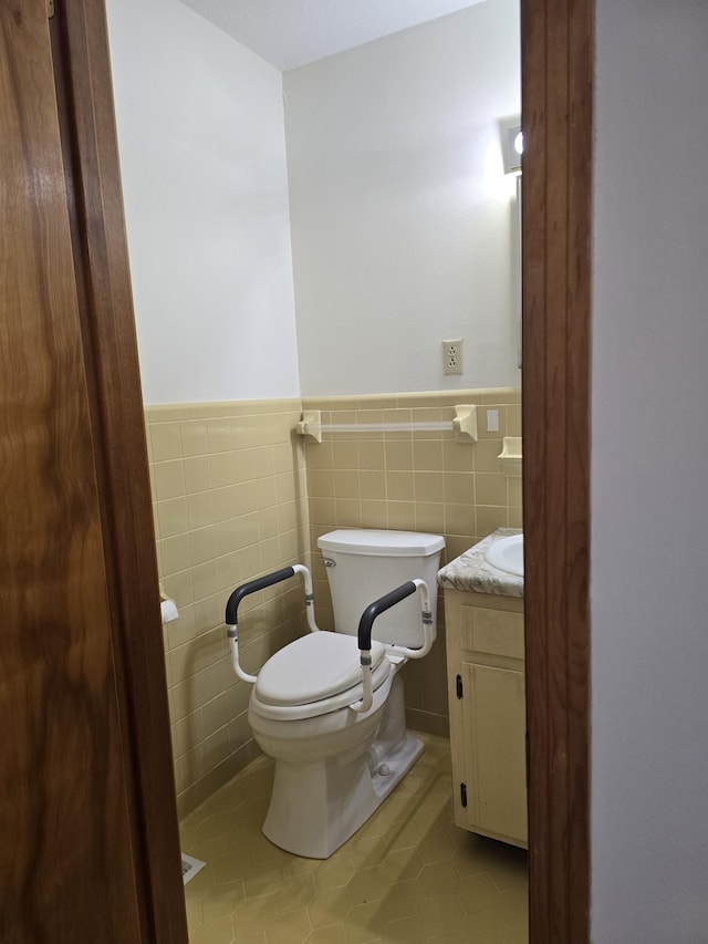 bathroom featuring tile patterned flooring, vanity, toilet, and tile walls