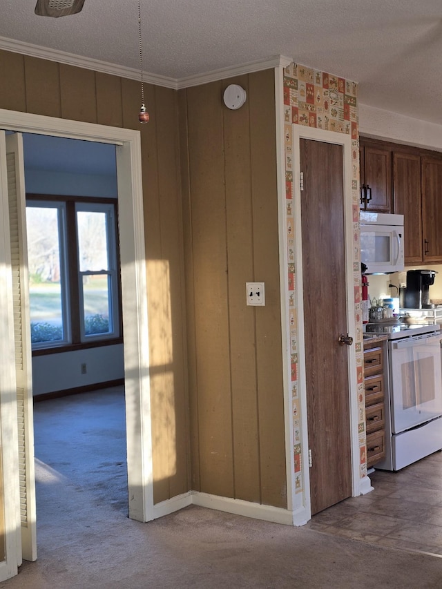 kitchen featuring carpet, white appliances, a textured ceiling, and ornamental molding