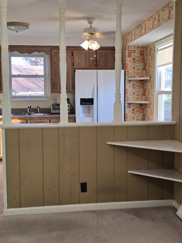 kitchen featuring carpet flooring, ceiling fan, white refrigerator with ice dispenser, and sink