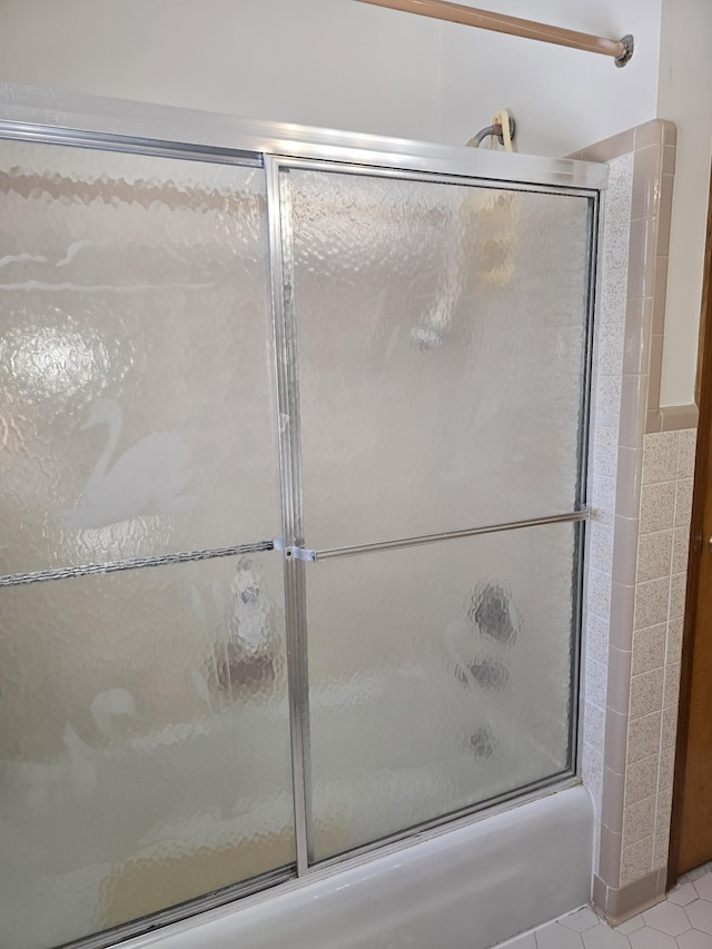 bathroom with tile patterned flooring, combined bath / shower with glass door, and tile walls