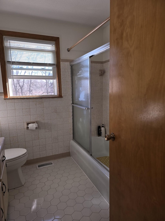 full bathroom with tile patterned floors, vanity, shower / bath combination with glass door, and tile walls