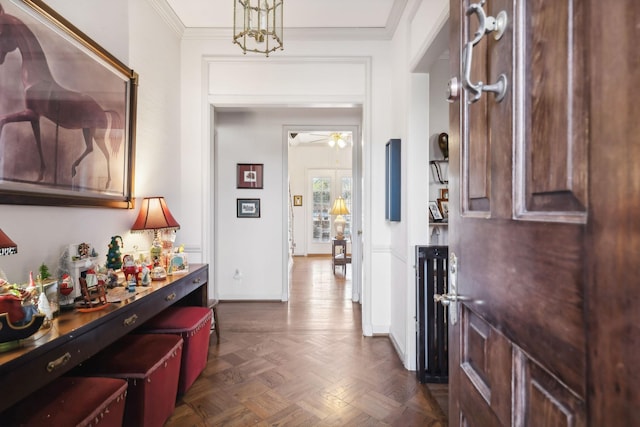 foyer featuring dark parquet floors, ceiling fan with notable chandelier, and ornamental molding