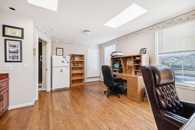 office with light wood-type flooring and a skylight