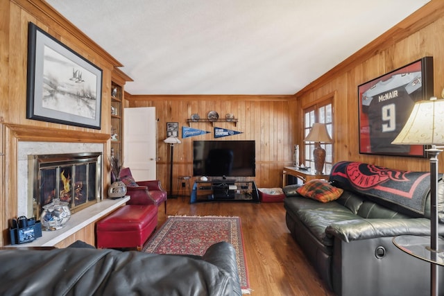 living room with a premium fireplace, dark hardwood / wood-style flooring, crown molding, and wooden walls