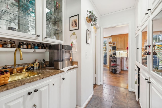 bar featuring sink, dark wood-type flooring, crown molding, dark stone counters, and white cabinets