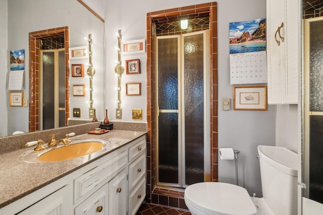 bathroom featuring tile patterned flooring, vanity, toilet, and an enclosed shower