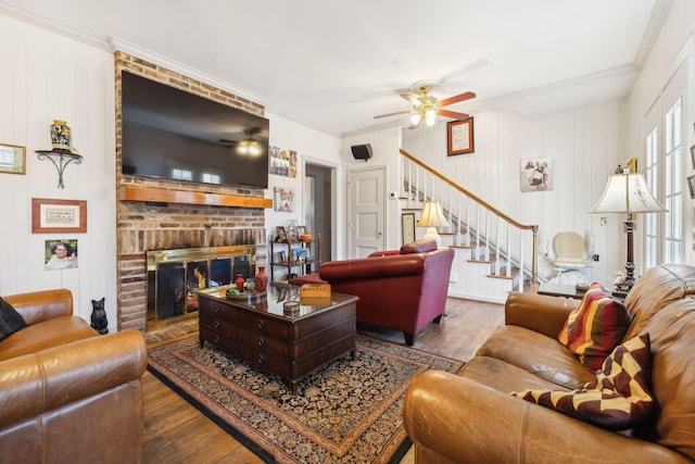 living room with hardwood / wood-style floors, ceiling fan, crown molding, and a fireplace