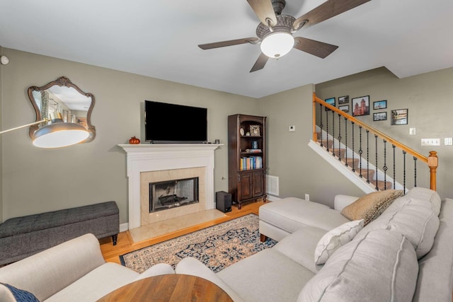 living room featuring a tile fireplace, ceiling fan, and hardwood / wood-style flooring