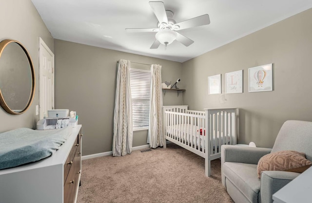 carpeted bedroom with ceiling fan and a nursery area