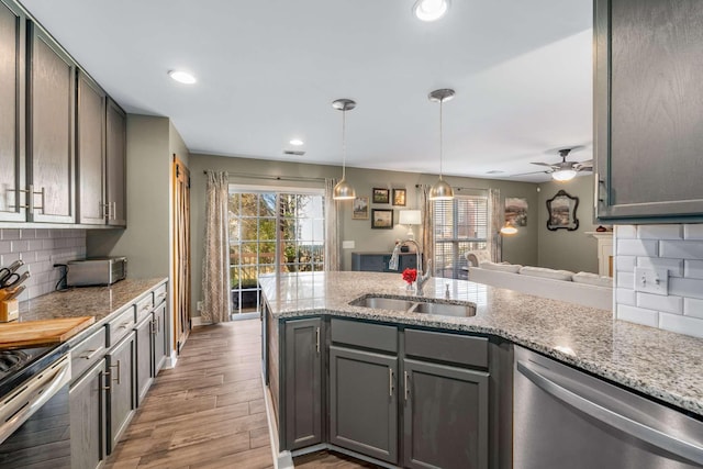 kitchen featuring sink, stainless steel dishwasher, ceiling fan, hardwood / wood-style flooring, and tasteful backsplash