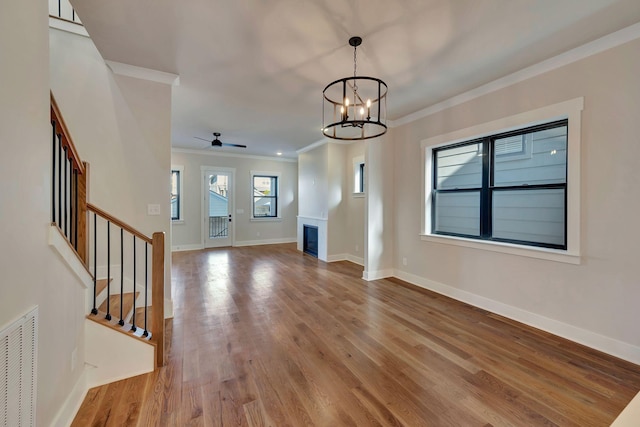 unfurnished living room featuring light wood-type flooring, ceiling fan with notable chandelier, and crown molding