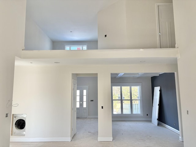 hall featuring plenty of natural light, a high ceiling, and baseboards