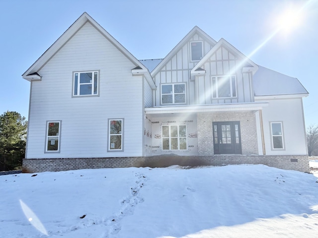 snow covered back of property featuring french doors