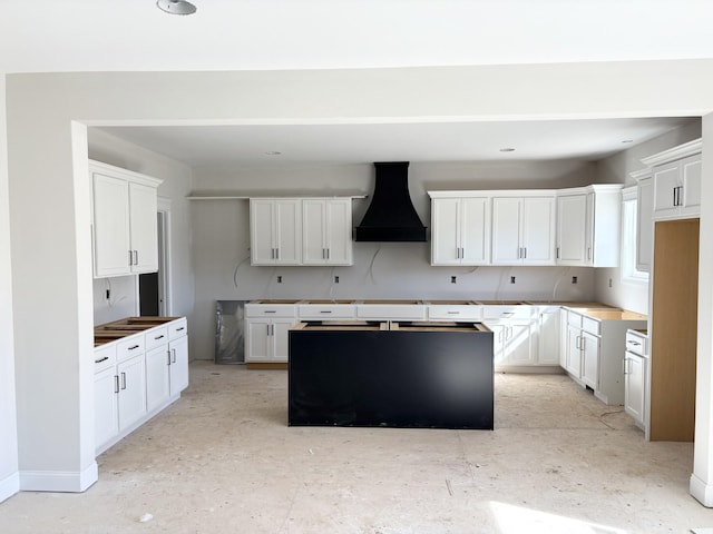 kitchen featuring custom range hood, white cabinetry, and a center island