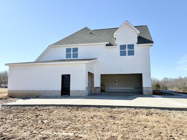 exterior space featuring an attached garage, brick siding, and roof with shingles