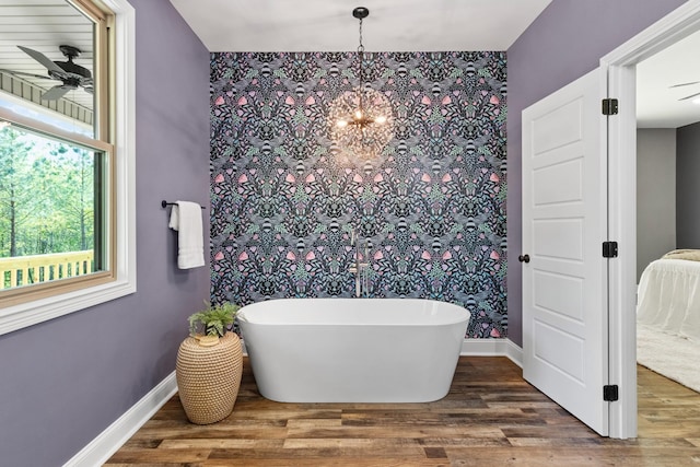 bathroom featuring a tub to relax in, hardwood / wood-style floors, and ceiling fan with notable chandelier