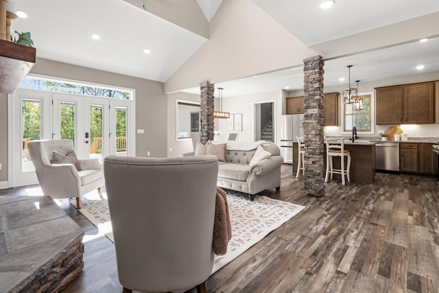 living room with dark wood-type flooring, high vaulted ceiling, french doors, sink, and ornate columns