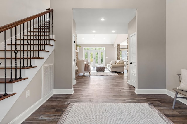 foyer with dark hardwood / wood-style floors, lofted ceiling, and french doors