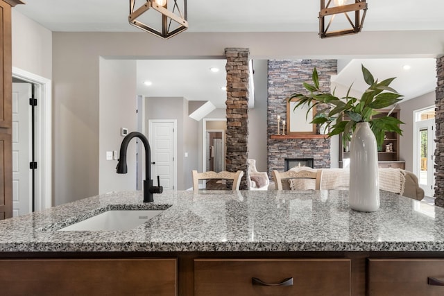 kitchen with light stone countertops, a stone fireplace, and sink