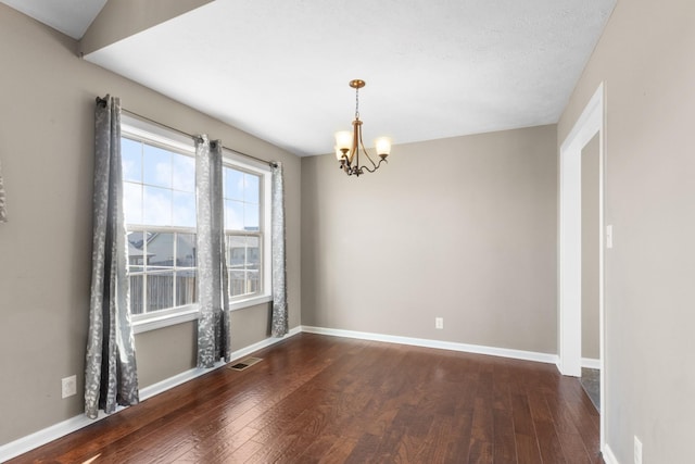 spare room with dark hardwood / wood-style flooring, a textured ceiling, and a chandelier