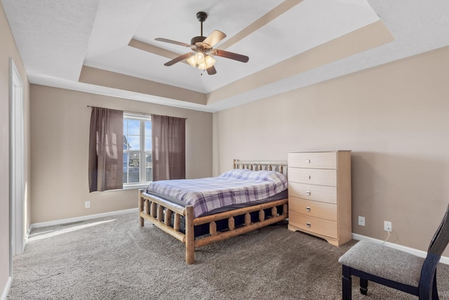 bedroom with ceiling fan, carpet floors, and a tray ceiling