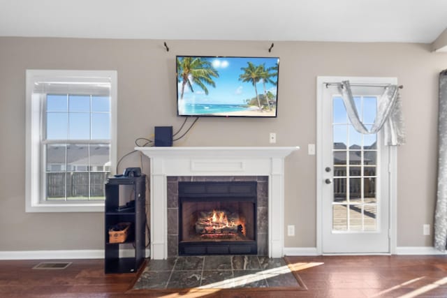 living room with a tiled fireplace and dark hardwood / wood-style flooring