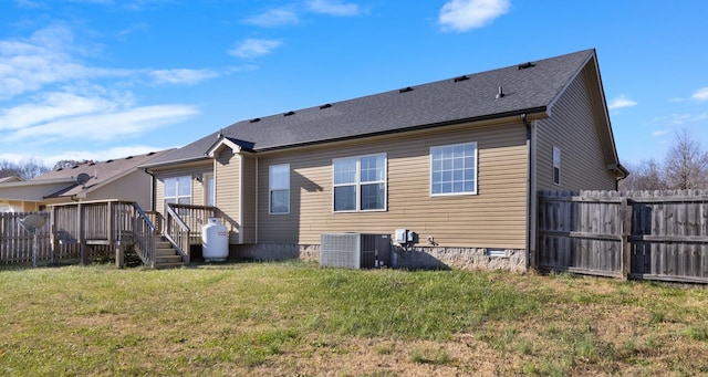 rear view of property featuring a lawn, a wooden deck, and central air condition unit