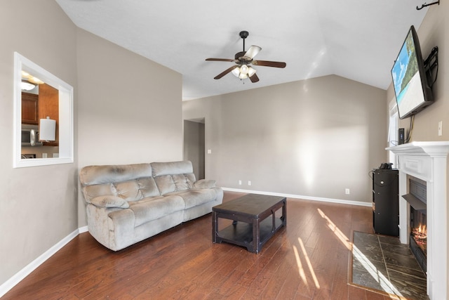 living room with a tile fireplace, lofted ceiling, ceiling fan, and dark wood-type flooring