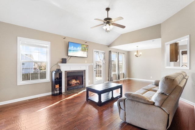 living room featuring a fireplace, ceiling fan with notable chandelier, dark wood-type flooring, and lofted ceiling