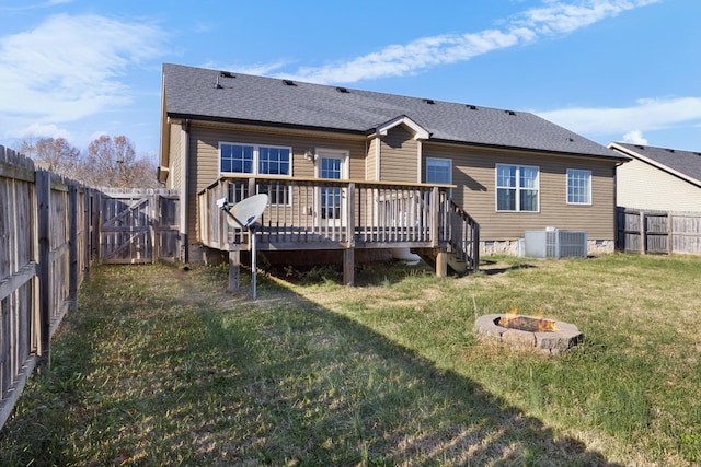 back of property with a lawn, an outdoor fire pit, a wooden deck, and central AC