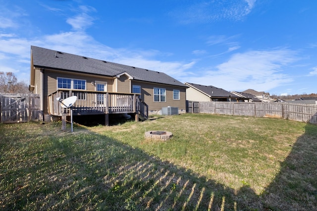 back of property with cooling unit, a deck, an outdoor fire pit, and a yard