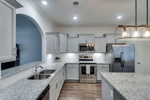 kitchen featuring light stone counters, stainless steel appliances, dark wood-type flooring, sink, and pendant lighting