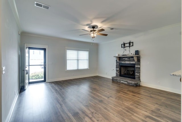 unfurnished living room with ceiling fan, a stone fireplace, crown molding, and dark wood-type flooring