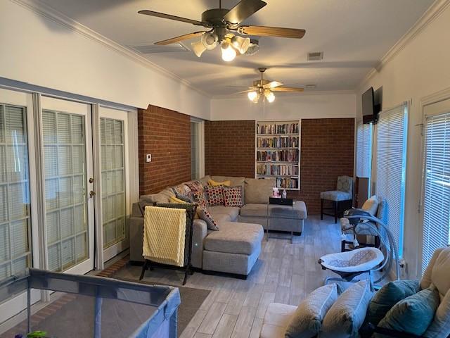 living room with hardwood / wood-style floors, french doors, crown molding, ceiling fan, and brick wall