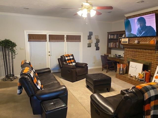 living room featuring carpet flooring, ceiling fan, ornamental molding, and a brick fireplace