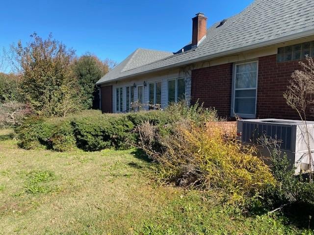 view of side of property featuring a lawn and cooling unit