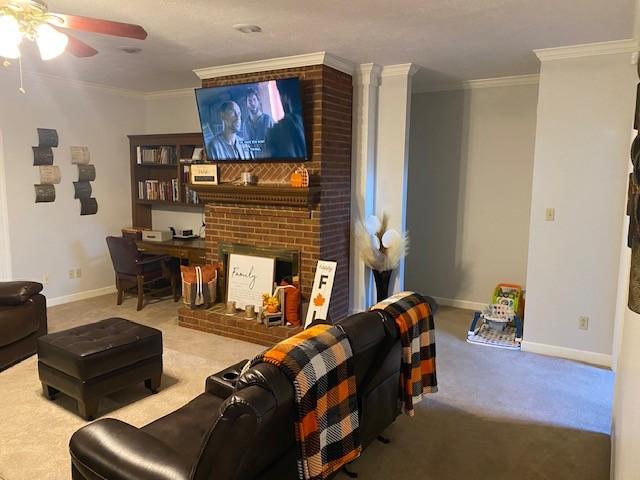 carpeted living room with ceiling fan, ornamental molding, and a fireplace